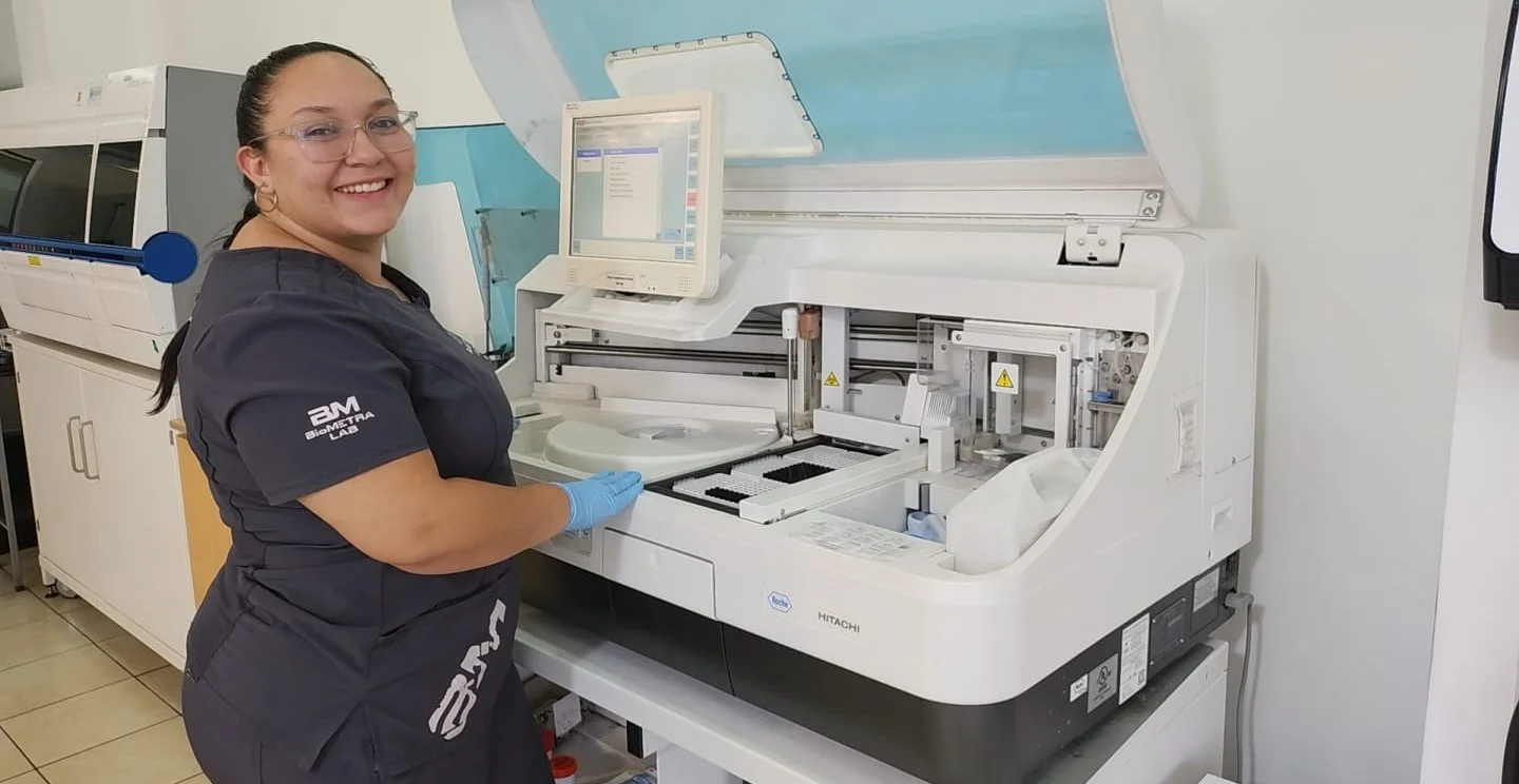Doctora de BioMETRA Lab sonriendo frente al equipo de química clínica